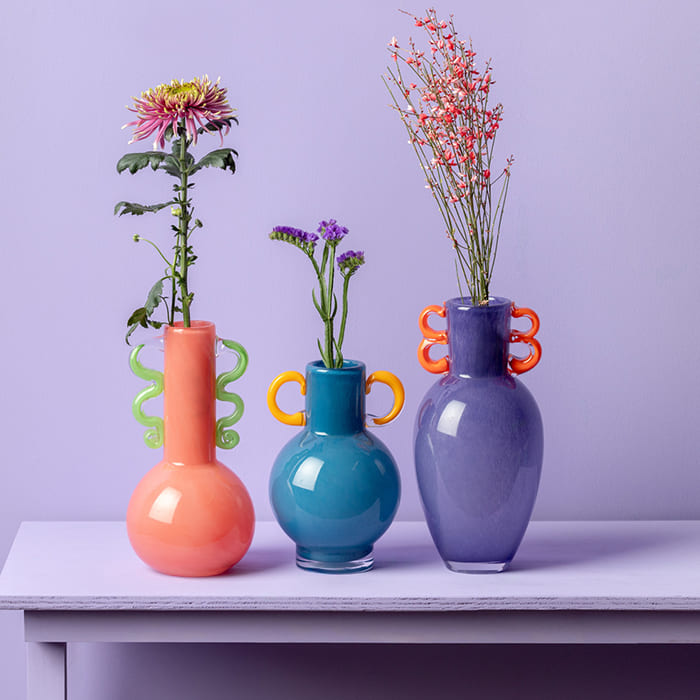 Vasi Fiesta Glass di Present Time in vetro colorato con manici decorativi e forme giocose.